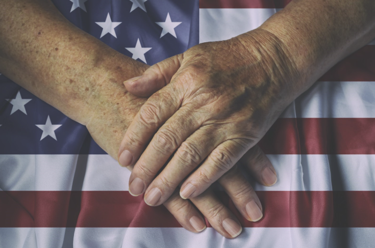 Close-up of senior hands gently folded on top of an American flag.